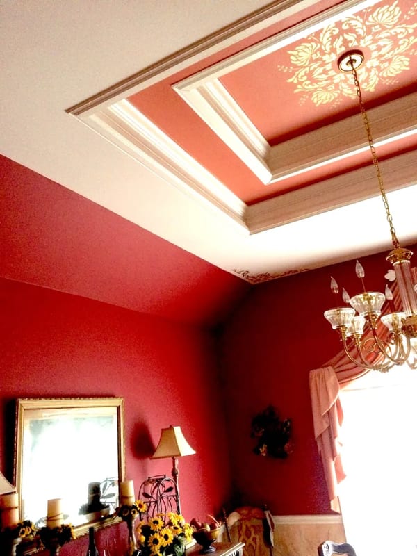 Deep red painted room with a white coffered ceiling and chandelier